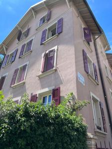 a tall building with purple doors and windows at A deux pas du lac Leman ( Ouchy) joli appartement in Lausanne