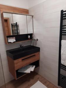 La salle de bains est pourvue d'un lavabo noir et d'un miroir. dans l'établissement Apartments Brunnmeisterhof, à Salzbourg