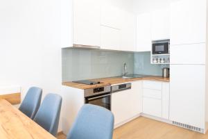 eine Küche mit weißen Schränken, blauen Stühlen und einem Tisch in der Unterkunft Modern 3 room apartment in a prime location in Wien
