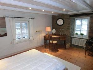 1 dormitorio con 1 cama, escritorio y ventanas en Haus-Hoeppches en Blankenheim