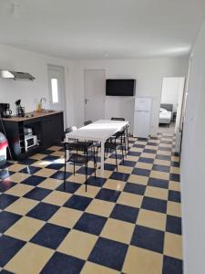eine Küche mit einem Tisch und einem karierten Boden in der Unterkunft Petite maison en bord de Loir in La Flèche