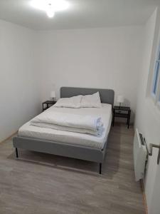 ein Schlafzimmer mit einem Bett in einem weißen Zimmer in der Unterkunft Petite maison en bord de Loir in La Flèche