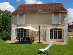 une maison avec une table et un parasol dans la cour dans l'établissement Le Domaine des Cyclamens, à Verneuil-sur-Indre