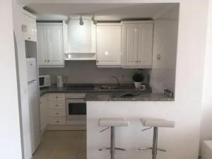 a kitchen with white cabinets and a counter with stools at Casa JC in Orihuela Costa