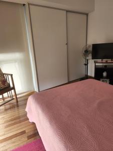 um quarto com uma cama rosa e uma cadeira em Apartamento Av kennedy y Cerviño a metros embajada EEUU em Buenos Aires
