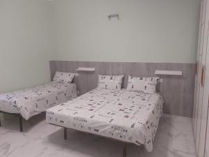 1 dormitorio con 2 camas, mantas blancas y almohadas en EL MAR casa vacanza Lavinio mare, en Anzio