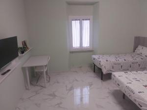 Habitación blanca con 2 camas y mesa en EL MAR casa vacanza Lavinio mare, en Anzio