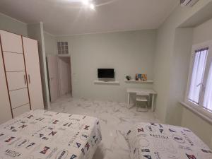 Habitación blanca con cama y TV en EL MAR casa vacanza Lavinio mare, en Anzio