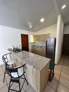 uma cozinha com um balcão e cadeiras e um frigorífico em CORONADO VILLA VICTORIA em San Carlos