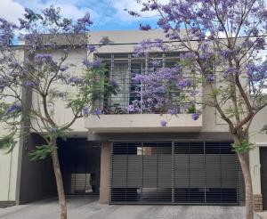 a building with purple flowering trees in front of it at Departamento Godoy Cruz Mendoza in Godoy Cruz