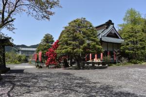 een huis met een boom met rode bloemen ervoor bij ゆののうち in Fujinomiya