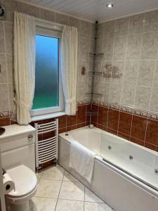 a bathroom with a tub and a toilet and a window at Stunning views in Lochgoilhead +7 photos