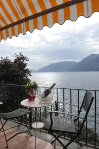 a table with a bottle of wine and chairs on a balcony at Nest on The Lake in Marone