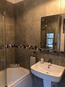 La salle de bains est pourvue d'un lavabo, d'une baignoire et d'un miroir. dans l'établissement Rectory Cottage. Close to Enniskillen and lakes., à Enniskillen