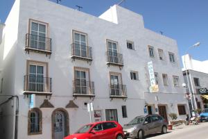 un edificio blanco con coches estacionados frente a él en Hostal El Yunque, en Conil de la Frontera