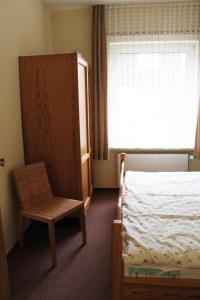 a bedroom with a bed and a chair and a window at Haus Strandgang, Whg 8 in Kellenhusen