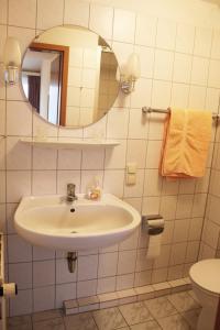 Haus Strandgang, Whg 11 في كيلينهوسن: حمام أبيض مع حوض ومرآة
