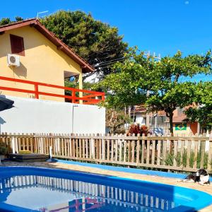 a swimming pool in front of a fence and a house at Residencial Bem Estar in Bombinhas