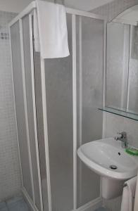 a white bathroom with a shower and a sink at Hotel Villa Argentina in Riomaggiore