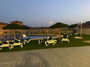 un grupo de sillas y sombrillas junto a una piscina en Apartamento nuevo con piscina en la envía golf aguadulce Almería, en La Envía