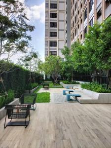 a park with benches and tables in front of a building at Two bedroom condo with rooftop pool in Ban Talat Rangsit