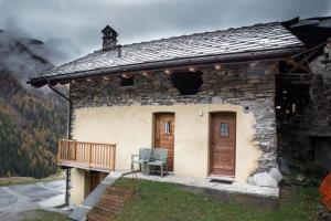 a small stone house with a wooden door and a deck at Le Grand Coeur - Monolocale di montagna con stufa in Nus