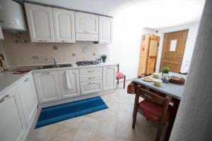 uma cozinha com armários brancos, uma mesa e um lavatório em Le Grand Coeur - Monolocale di montagna con stufa em Nus