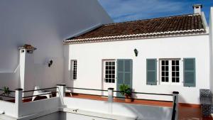 ein weißes Haus mit grünen Rollläden und einem Balkon in der Unterkunft Casa Arcanjo in Lagoa