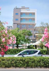 ソットマリーナにあるHotel Jonniのピンクの花の咲く建物の前に停められた車