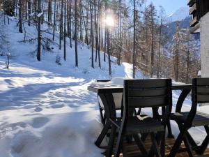 two chairs and a table in the snow at L'Orée des Bois - Studio avec terrasse au calme in Les Orres