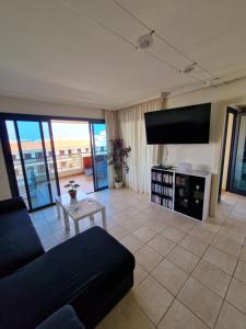 a living room with a couch and a flat screen tv at Large terrace with views on the cliffs at Balcon De Los Gigantes in Puerto de Santiago