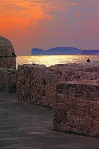 una pared de piedra junto al océano al atardecer en Home Feeling Mascagni - Bilocale en Alguer
