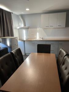 eine Küche mit einem Holztisch und Stühlen in der Unterkunft Paris en train Area Studios avec salles de bain et kitchenettes privées ou chambres avec salles de bain et cuisines communes in Persan