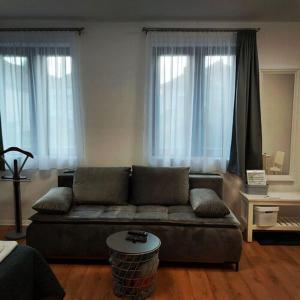 a living room with a couch and two windows at Kis Ház Apartman in Szigetvár