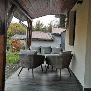 un patio al aire libre con 2 sillas y un sofá en Kis Ház Apartman, en Szigetvár