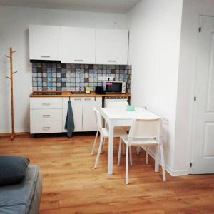 a kitchen with a white table and white chairs at Kis Ház Apartman in Szigetvár