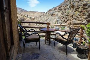a table and chairs on a balcony with a view at the suwgra-Al-Jabal Al-Akdar in Sūkirah