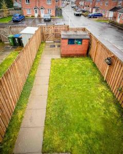 a garden with a wooden fence and grass at Loch Leven Getaway - 2 bed house in Kinross
