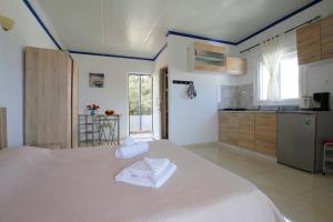 a bedroom with a large white bed and a kitchen at Paradis Studios in Archangelos