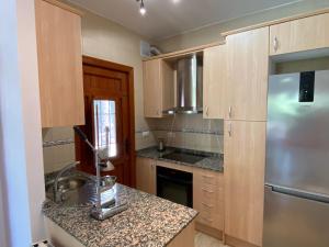 cocina con armarios de madera y encimera de granito en Casa Mirador views near coast, en Mazarrón