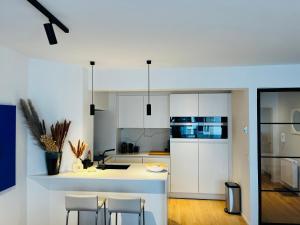 eine Küche mit weißen Schränken und weißen Arbeitsflächen in der Unterkunft Chez Coceau - Luxery apartment with sea view in Ostende