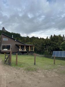 un granero con una valla y una casa con paneles solares en Cabaña Meliquina en Villa Meliquina