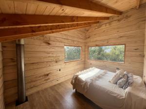 Cabaña de madera con 1 cama en una habitación con 2 ventanas en Cabaña Meliquina en Villa Meliquina