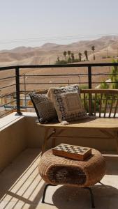 a bench on a balcony with pillows and a book at סיני 48 מלון דירות בוטיק in Vered Yeriho