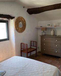 1 dormitorio con cama, silla y vestidor en Maison de village avec terrain et piscine dans le Parc Régional du Haut Languedoc, en Le Pradal