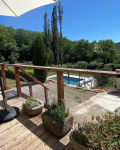 una terraza de madera con una mesa y algunas plantas en Maison de village avec terrain et piscine dans le Parc Régional du Haut Languedoc, en Le Pradal