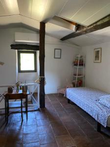 Un dormitorio con una cama y una mesa. en Maison de village avec terrain et piscine dans le Parc Régional du Haut Languedoc, en Le Pradal