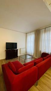 オレッジョにあるAppartamento La Corteのリビングルーム(赤いソファ、テレビ付)