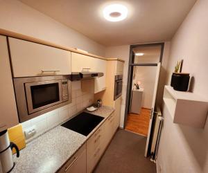 una pequeña cocina con armarios blancos y microondas en Komfortable Ferienwohnung Auf dem Höchsten, en Dortmund