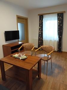 a living room with a table and chairs and a television at Penzion Villa Marion in Mariánské Lázně